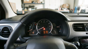 Photo réaliste du tableau de bord d’une Citroën C3 avec un voyant moteur allumé, dans une ambiance de garage sobre et feutrée.